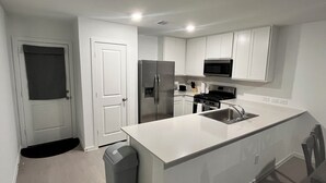 A modern kitchen with white cabinets, a stainless steel refrigerator, a microwave, and a sink. - Brand New Cozy 3 BD w/Fiber optic nested in quite Cul De SAC. Ultra modern (Conroe)