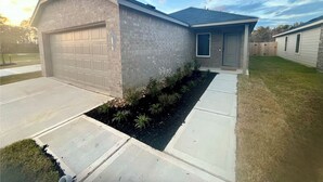 A two-story house with a garage, a front door, and a small front yard with landscaping. - Brand New Cozy 3 BD w/Fiber optic nested in quite Cul De SAC. Ultra modern (Conroe)
