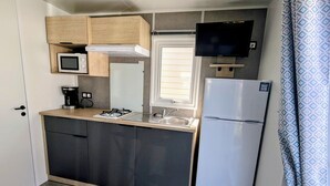 Une petite cuisine équipée d’un four à micro-ondes, d’une cuisinière, d’un évier et d’un réfrigérateur.