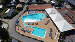 Vue aérienne d’un quartier résidentiel avec une piscine entourée de chaises longues et de parasols.