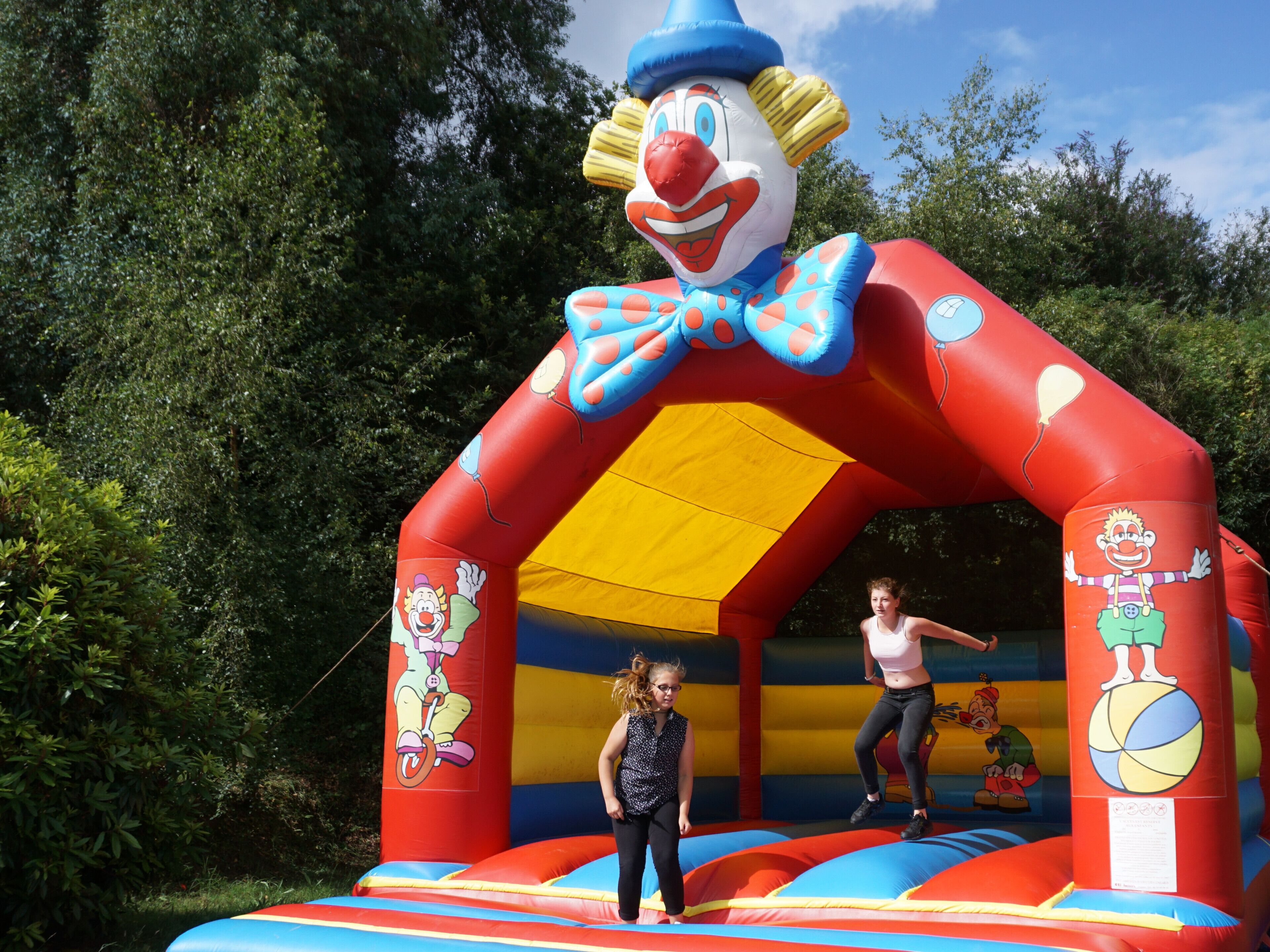 An inflatable bounce house with cartoon characters and a clown design.