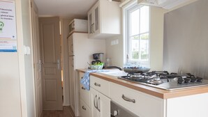 Una cocina con armarios blancos, estufa a gas y ventana que proporciona luz natural.
