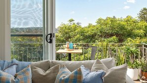A balcony with a sofa, a table with drinks, and potted plants. - Shoreleaf Haven Moments from Waves and Seaside Eats (Dee Why)