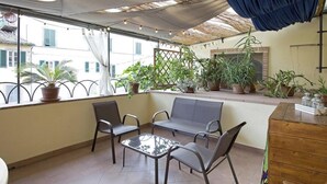 A balcony with seating, potted plants, and a view of buildings. - Casa San Girolamo, historic flat with terrace in Lucca's City Center (Lucca)
