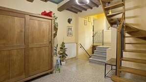 A wooden staircase with a metal railing, a wooden cabinet, and a potted plant. - Casa San Girolamo, historic flat with terrace in Lucca's City Center (Lucca)