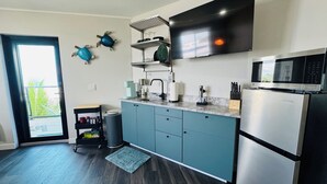Una cocina moderna con armarios color turquesa, un refrigerador de acero inoxidable, un microondas y un ventanal grande.