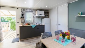 A compact kitchen with a dining area, featuring a wooden table, chairs, and a small refrigerator. - Truffe - Confort 2 - 5p (Saint-Geniès)