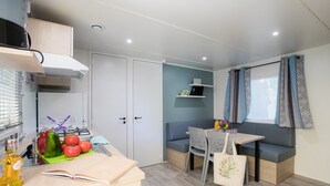 A compact kitchenette with a stove, sink, and a small dining area with a table and chairs. - Truffe - Confort 2 - 5p (Saint-Geniès)