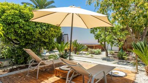 A wooden deck with two lounge chairs and a large umbrella, surrounded by greenery and a view of the sea. - Villa Levante - Taviano (Taviano)