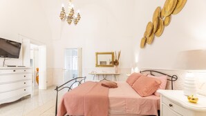 A bedroom with a bed, bedside table, lamp, and a television on a stand. - Villa Levante - Taviano (Taviano)
