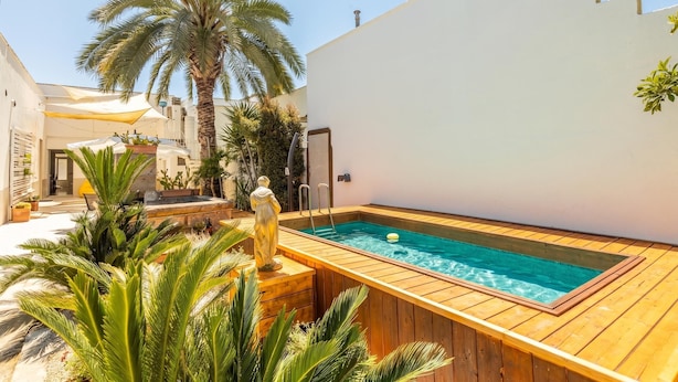A pool with a wooden deck, surrounded by plants and a statue. - Villa Levante - Taviano (Taviano)
