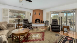 A living room with a fireplace, two leather chairs, a sofa, and a ceiling fan. - Spacious Catalina Mountain View Retreat 30+ min (Tucson)