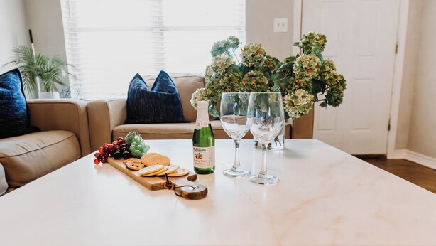 Une table en marbre avec une bouteille de vin, deux verres, une assiette de fruits et un tire-bouchon.