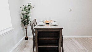 Une table à manger dressée avec des assiettes, des verres et une petite plante.