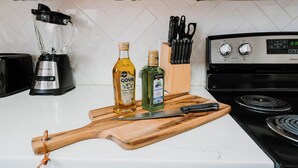 Une cuisine équipée d’un mixeur, de bouteilles d’huile d’olive, d’une planche à découper avec un couteau et d’une cuisinière.