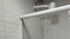 Une salle de bain comprenant des toilettes, un espace douche et un sol carrelé.