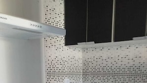 Une petite cuisine équipée d’un évier, d’un tabouret et d’une hotte aspirante.