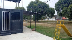 Un petit bâtiment à l’extérieur noir, avec un toit en métal et un toboggan jaune.