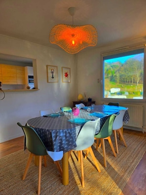 A dining area with a round table, chairs, and a unique orange pendant light.