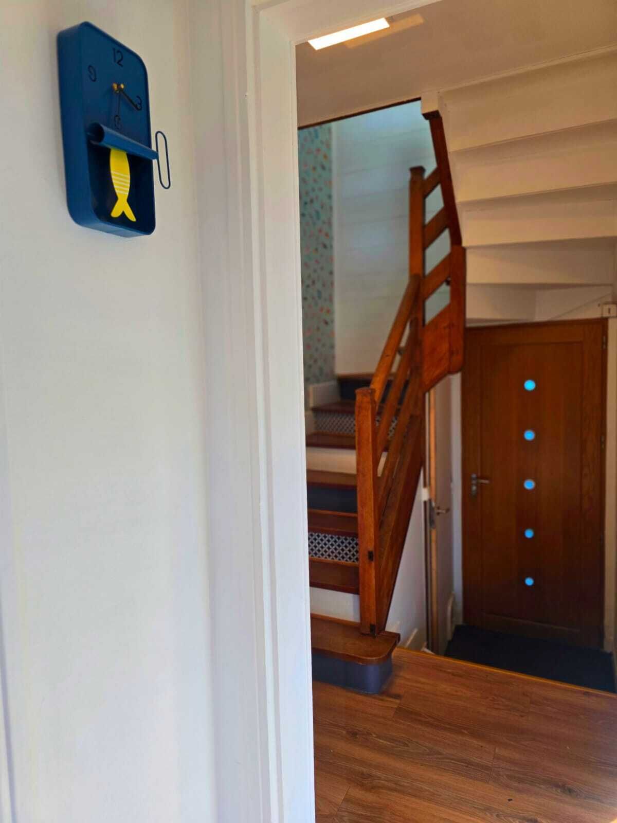 A staircase with wooden steps and a handrail, leading to a door with a light switch and a circular light fixture.