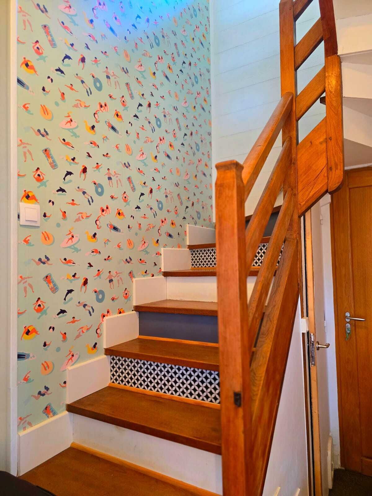 Eine Holztreppe mit einer hellen Wand, die ein verspieltes Muster aus verschiedenen Figuren zeigt.