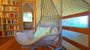 Une pièce avec un fauteuil suspendu, des étagères en bois et un mur orné de motifs.