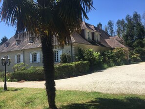 A large, two-story house with a brick exterior, multiple windows with shutters, and a gravel driveway. - DORDOGNE VACATION RENTALS (Thiviers)