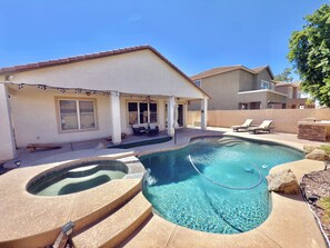 A residential swimming pool with a hot tub, lounge chairs, and a covered patio area. - Luxury Desert Oasis (Phoenix)