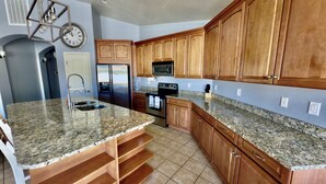 Eine Küche mit Granit Arbeitsplatten, Holzschränken und Edelstahlgeräten, inklusive Backofen.
