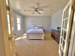 A bedroom with a bed, a ceiling fan, a dresser, and a window. - Luxury Desert Oasis (Phoenix)