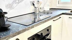 A modern kitchen with a marble backsplash, a black countertop, and stainless steel appliances. - Il Rifugio (Marettimo)
