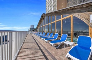 A sun deck with blue lounge chairs and a pool area on a cruise ship. - Direct Oceanfront with Private Balcony (Myrtle Beach)