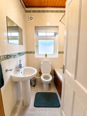 A bathroom with a sink, toilet, and window.