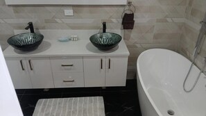 Ein Badezimmer mit zwei Waschbecken, einer Badewanne und einem Handtuchhalter.