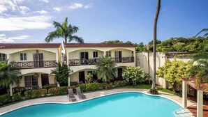 A hotel with a swimming pool, balconies, and lush greenery. - Willow Estates Luxury Condo – Spacious 2BR 2BA Pool and Las Terrenas Beaches (Las Terranas)