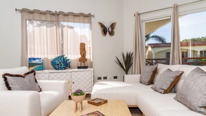 Uma sala de estar moderna com sofá, mesa de centro, objetos decorativos e uma janela grande com vista.