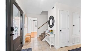 A modern hallway with a wooden bench, a white console table with a mirror, and a staircase leading to another level. - Winter snowbirds retreat- Monthly discount available for min 3 month stay (Gulf Breeze)