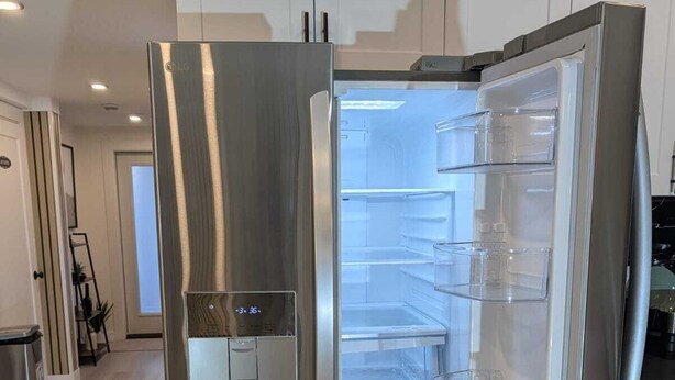 A stainless steel refrigerator with a digital display, a freezer compartment, and multiple shelves. - Serene 2-bedroom apartment in Calgary, perfect for your getaway- The Loft Modern (Calgary)