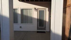 A house entrance with a front door, two windows with curtains, and a small porch area. - Serene 2-bedroom apartment in Calgary, perfect for your getaway- The Loft Modern (Calgary)