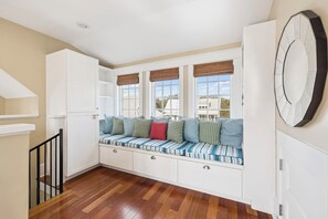 A room with a built-in bench with storage drawers, large windows with blinds, and a clock on the wall. - Carriage House | Pool Access | Dogs Allowed (Rosemary Beach)