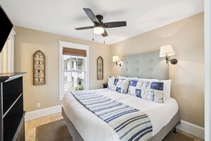 A bedroom with a bed, ceiling fan, wall sconces, and decorative wall art. - Carriage House | Pool Access | Dogs Allowed (Rosemary Beach)
