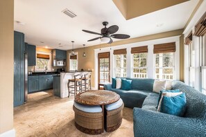 A spacious living area with a large sofa, a dining table with chairs, and a kitchen area with cabinets and a refrigerator. - Carriage House | Pool Access | Dogs Allowed (Rosemary Beach)
