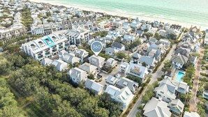An aerial view of a coastal residential area with houses, a beach, and a large building with a swimming pool. - Community Pool Access with Carriage (Rosemary Beach)