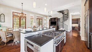 A spacious kitchen with a large island, dark wood flooring, and a modern design. - Community Pool Access with Carriage (Rosemary Beach)