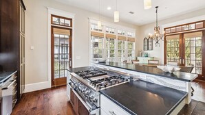 A spacious kitchen with a large island, wooden cabinets, and a gas stove. - Community Pool Access with Carriage (Rosemary Beach)