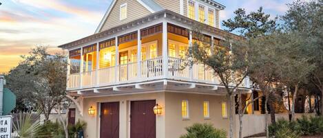 A two-story house with a balcony, a garage, and a well-maintained garden.
