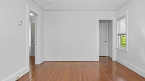 Ein geräumiges Zimmer mit Holzdielen, weißen Wänden und zwei Einbaustrahlern.