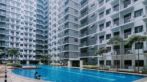 Ein modernes Apartmenthaus mit Schwimmbad, Balkonen und einem gefliesten Weg.