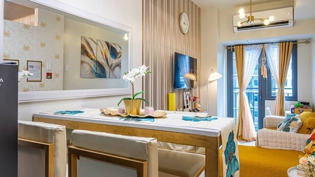 Ein modernes Hotelzimmer mit Essbereich, einem großen Spiegel, einer Uhr und einem Fenster mit Vorhängen.