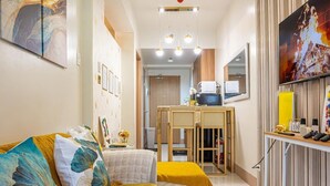 Ein Hotelzimmer mit einer Couch, einem kleinen Tisch, einem Fernseher und einem Spiegel.